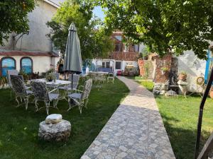eine Terrasse mit Tisch und Sonnenschirm im Rasen in der Unterkunft Pergamonpension in Bergama