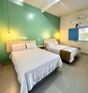 a bedroom with two beds and a green wall at Eco sítio encontro das aguas in Curuçá