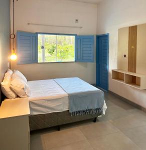a bedroom with a bed with blue shutters and a window at Eco sítio encontro das aguas in Curuçá +23 photos