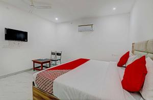 a bedroom with a bed with red pillows and a television at Hotel O Raghav & Banquet in Hasanganj