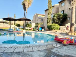 a swimming pool with an inflatablelatable boat next to a building at Modern Apt in Paphos Port - pool & 50 m to the sea in Paphos