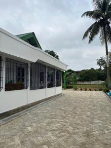 Un edificio blanco con una palmera al fondo. en ClubGreens, en Jorhat