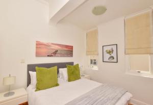 a white bedroom with a bed with green pillows at Dalebrook Place Kalk Bay near Tidal Pool in Kalk Bay