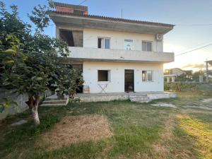 a white house with a tree in a yard at Garden Vila Apartment in Kamëz