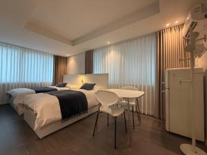 a bedroom with a bed and a table and a refrigerator at Dada Stay Hongdae in Seoul