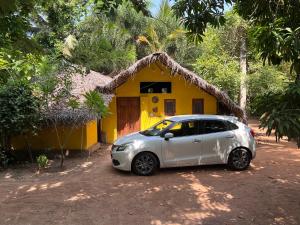 a small car parked in front of a yellow house at Vaakai Home Stay in Adampan