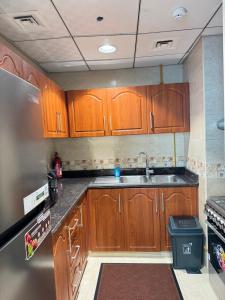Una cocina con gabinetes de madera y un refrigerador de acero inoxidable. en 2Bed Room Full Seaview, en Ajman
