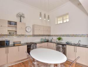 a white kitchen with a white table and chairs at Dalebrook Place Kalk Bay near Tidal Pool in Kalk Bay