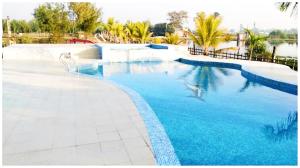 una piscina con agua azul y palmeras en Hotel Dream In Mandarmani Near Sea Beach AC OR NON AC ROOM, en Mandarmani
