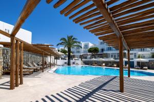 a swimming pool with lounge chairs and a building at Poseidon Hotel Suites in Mikonos