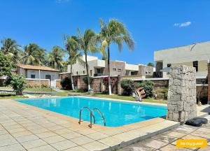 a swimming pool in front of a house with palm trees at Linda casa ampla próximo ao mar do Cumbuco in Guagiru