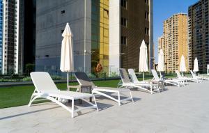 a row of lounge chairs and umbrellas on a patio at Intempo Apartment 13E by VivaMar in Benidorm