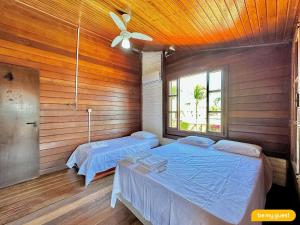 two beds in a room with wooden walls and a ceiling at Linda casa ampla próximo ao mar do Cumbuco in Guagiru +27 photos