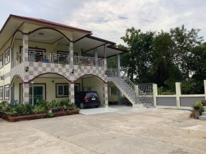 Una casa con balcón y un coche aparcado en la entrada. en CC Homestay, en Surin 5 fotos más
