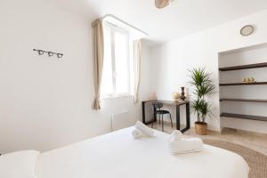 a white bedroom with a bed and a table at Suite Ecrin de pierre - Hypercentre - WiFi in Apt