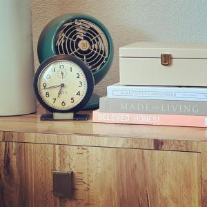 une horloge assise sur une étagère avec des livres dans l'établissement Fernando Flats, à Palm Beach Shores