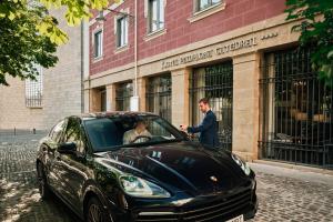 a man standing next to a black car in front of a building at Pamplona Catedral Hotel in Pamplona