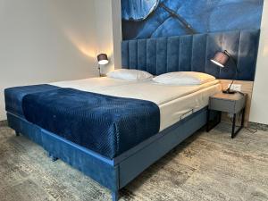 a bedroom with a bed with a blue headboard at Hotton Hotel in Gdynia