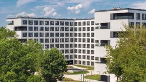 un edificio bianco con alberi di fronte di Zeitraum Raclawicka a Cracovia