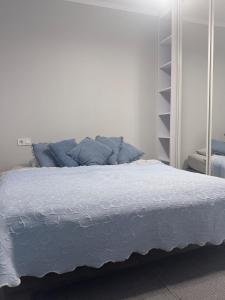 a white bed with blue pillows in a bedroom at Apartments in VODOGRAY Residential Complex Краєвид і охайність захоплюють дух! in Chernivtsi