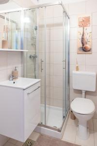a white bathroom with a shower and a toilet at Studio Apartma Leopold in Piran