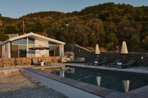 a pool with chairs and umbrellas next to a house at Sea You Soon & Spa 2 in Methana
