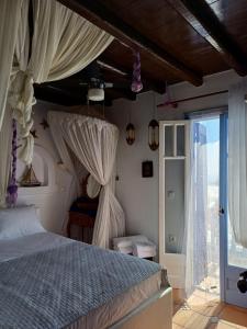 1 dormitorio con cama con dosel y puerta abierta en Serifos house, en Serifos Chora