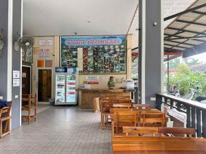 a restaurant with wooden tables and chairs and a counter at Khao Sok Inn Hostel in Khao Sok National Park