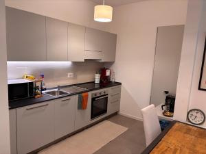 une cuisine avec des armoires blanches, un évier et un micro-ondes dans l'établissement Garden Roots - Carozzi Apartments, à Sesto San Giovanni 17 autres photos