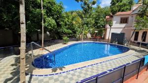 a pool with a palm tree in front of a house at Helios Villa in Auroville