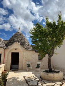 een gebouw met een boom en twee stoelen bij Nidus Petrae in Alberobello