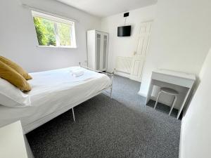 a white bedroom with a bed and a desk at Family Bungalow sleeps 4 in Wellington
