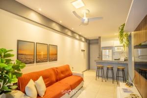 a living room with an orange couch and a kitchen at Apart in Condo w/ Pool and Gym STE0312 in Salvador