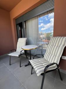 Un balcón con dos sillas y una mesa y una ventana. en Mitra Apartmani, en Zlatibor