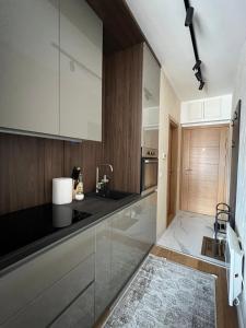 Una cocina con gabinetes blancos y una encimera negra. en Mitra Apartmani, en Zlatibor