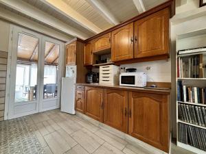 une cuisine avec des armoires en bois et un micro-ondes dans l'établissement Maison 3 pièces au cœur de Saint-Pierre d’Oléron, 6 couchages - FR-1-246A-359, à Saint-Pierre-dʼOléron