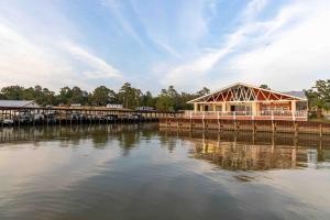 a building on a dock next to a body of water at A Calm and Cozy Lakeside Glamping Retreat Awaits in Onalaska
