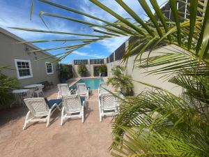 a patio with white chairs and a swimming pool at Puerta Del Sol Escape 1- 1brd-pool-central location in Oranjestad