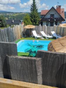 a backyard swimming pool with a wooden fence at Willa Rycerz in Niedzica Zamek