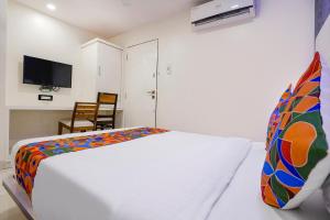 a white bedroom with a bed and a tv at FabHotel Golden Star in Mumbai