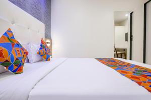 a bedroom with a white bed with colorful pillows at FabHotel Golden Star in Mumbai