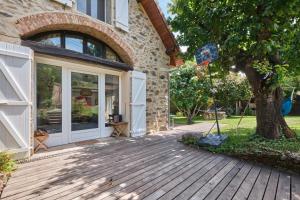 a house with a wooden porch with a tree at Jolie Maison En Pierres in Saint-Martin-de-la-Cluze