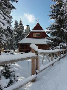 una baita di tronchi con una recinzione nella neve di Kubusiowa Chatka a Murzasichle
