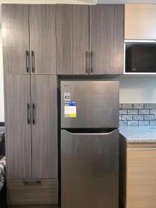 une cuisine avec un réfrigérateur en acier inoxydable et des armoires en bois dans l'établissement Pine Suites Tagaytay, à Tagaytay