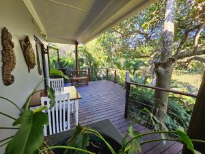a porch with a table and chairs and a tree at Leopard Corner Lodge in St Lucia