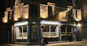 a building with a restaurant on a street at night at The Tap Rooms in Hexham