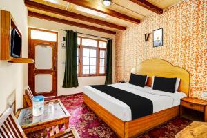 a bedroom with a bed and a table and a tv at Hotel O New Sun N Snow in Manāli