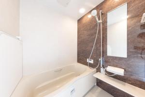 a bathroom with a bath tub and a mirror at Forest and Stars Akakura Luxe in Myoko +36 photos