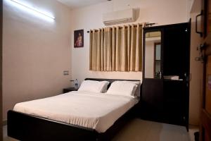a bedroom with a bed with white sheets and a window at K K Gardens in Palakkad