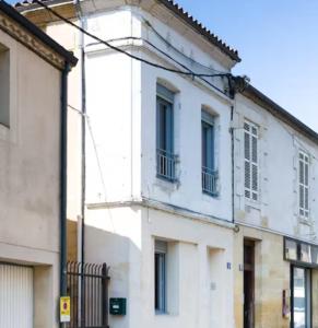 a white building with windows on a street at L'écrin rose, appartement coeur de ville de Bergerac in Bergerac +16 photos